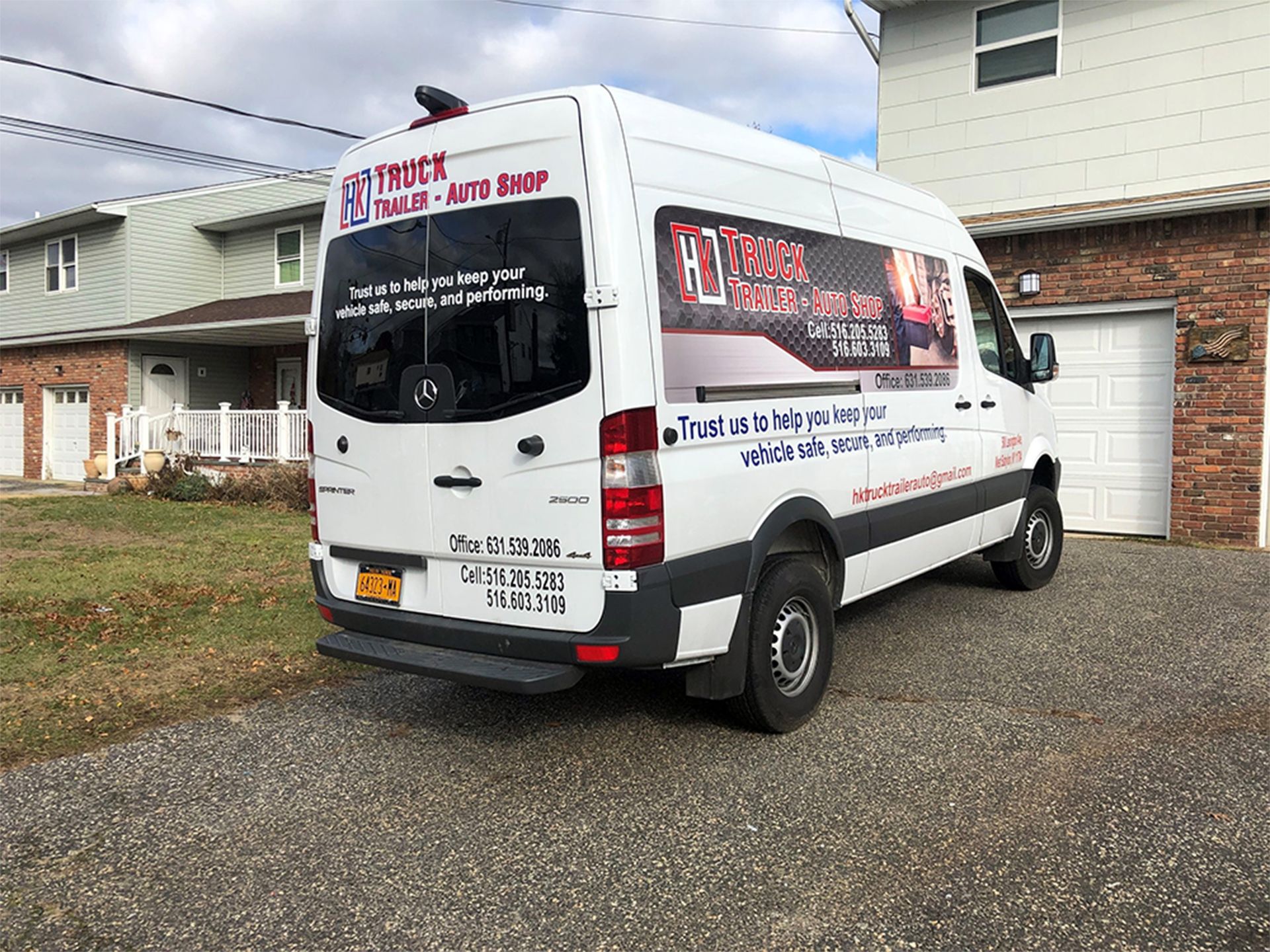 A white van is parked in front of a brick house.