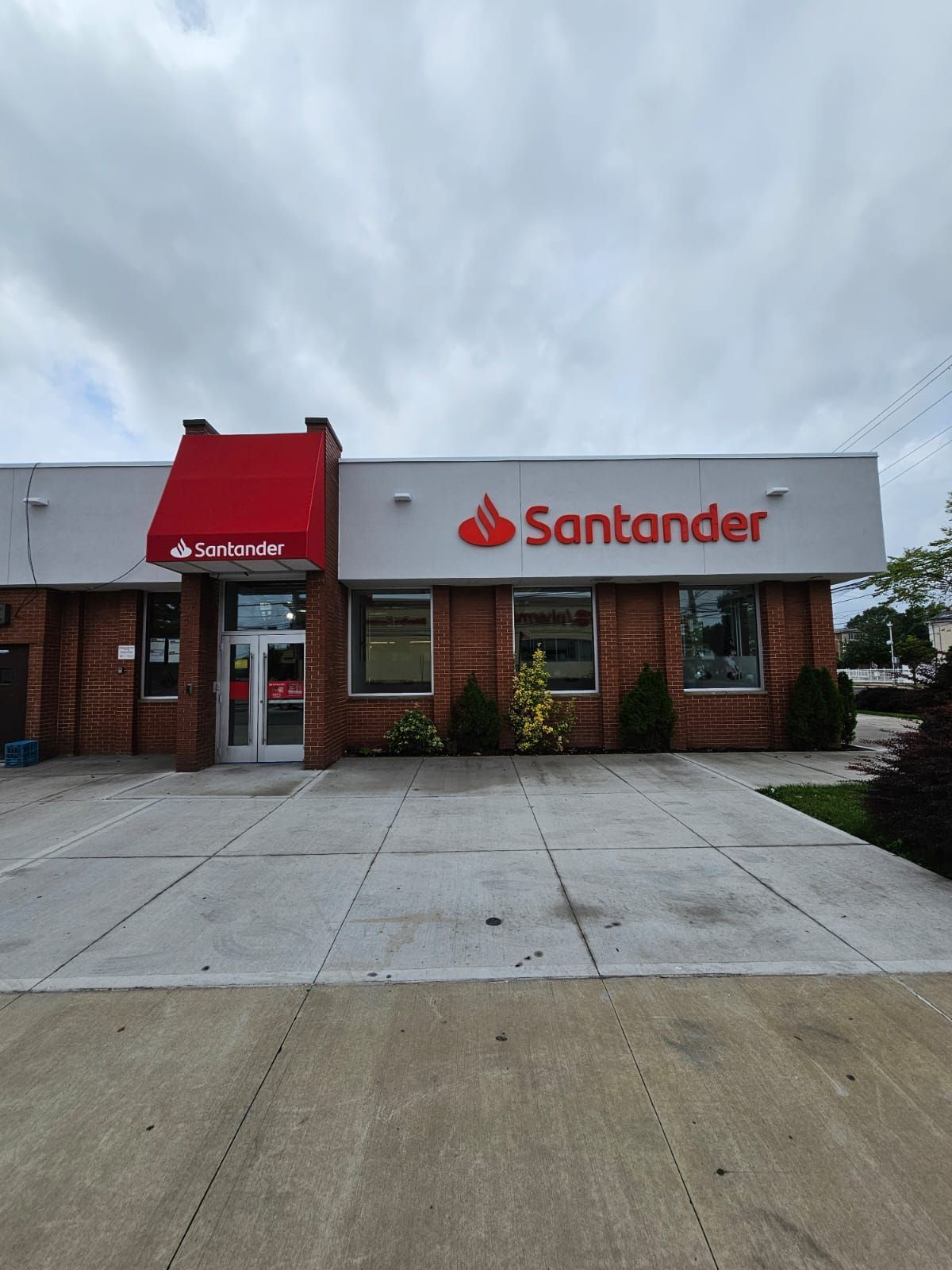 The front of a santander bank building with a red awning.