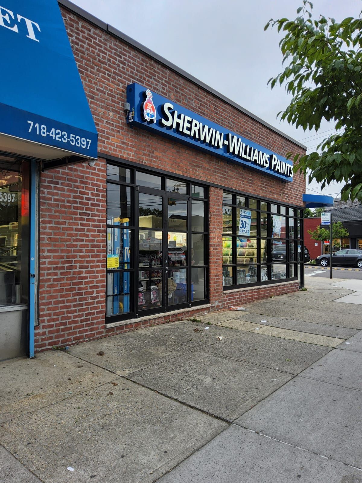 A brick building with a blue awning that says sherwin-williams paint