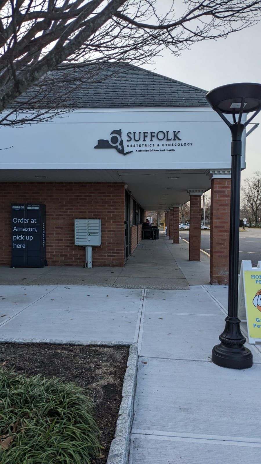 A brick building with a sign on the sidewalk in front of it.