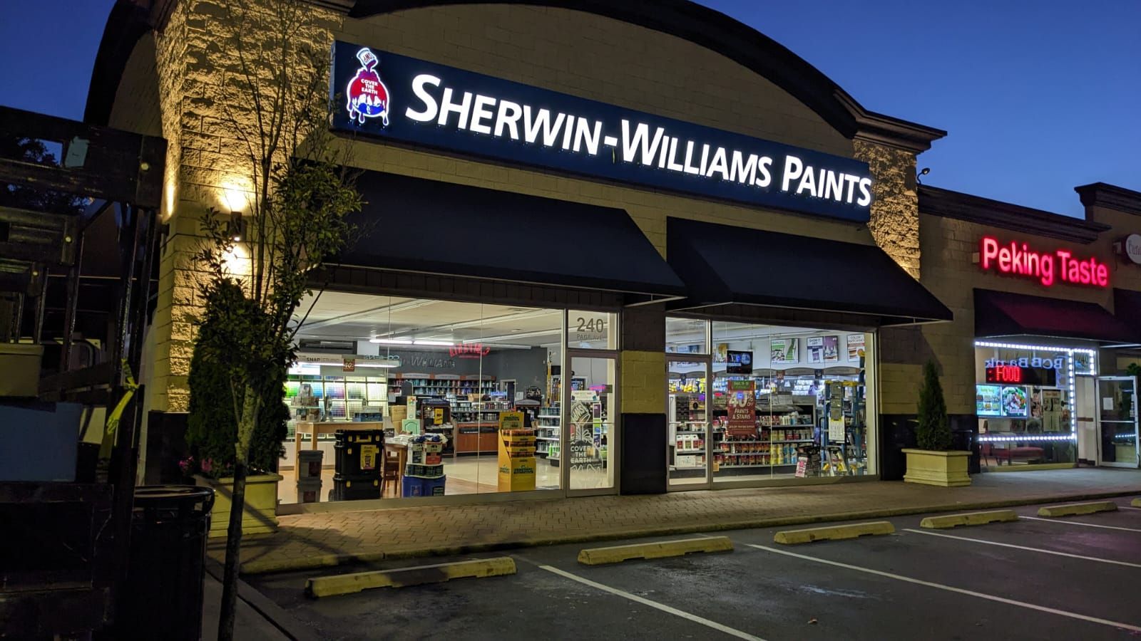 A sherwin williams paint store is lit up at night.
