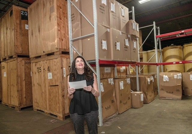A woman is standing in a warehouse holding a piece of paper