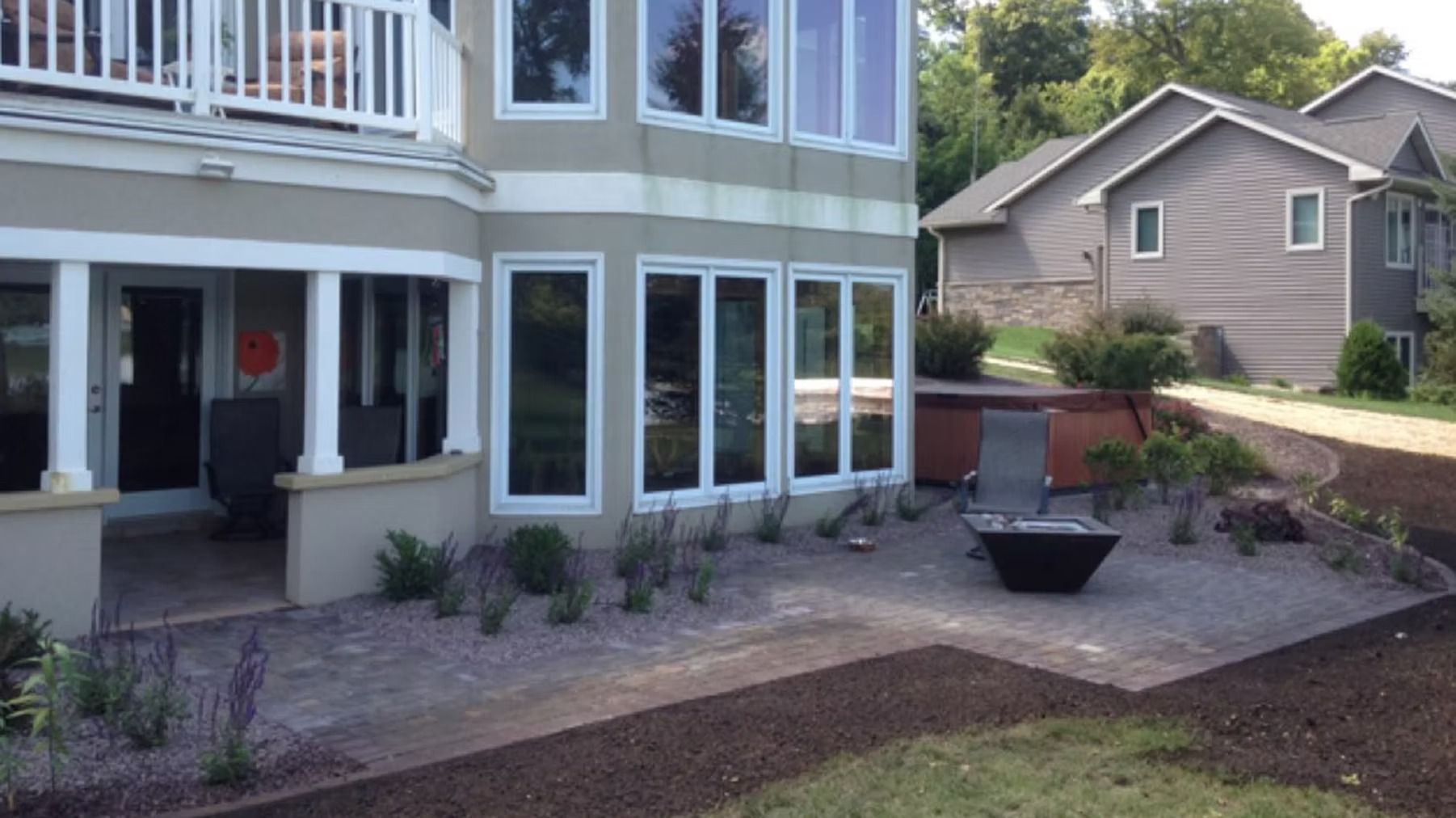 Backyard patio beside a house with potted plants and a neighboring home in the background