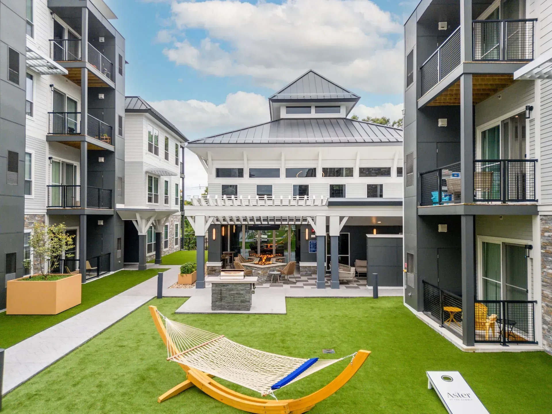 Apartment complex courtyard with buildings, a pergola, and hammock.