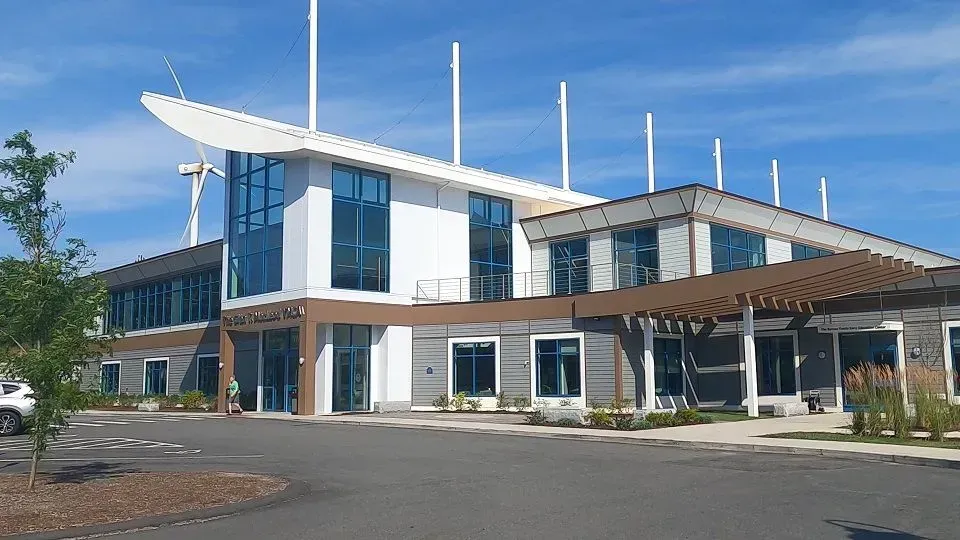 Modern building with white and gray exterior, blue windows, and a pergola.