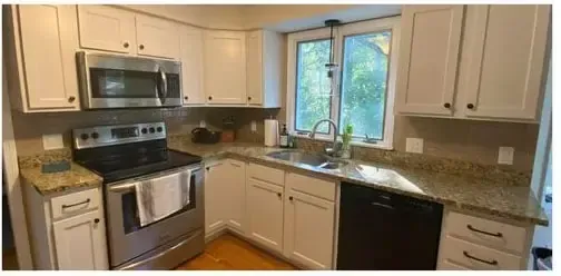 Modern kitchen with stainless steel appliances, cream cabinets, granite counters, and a window over the sink