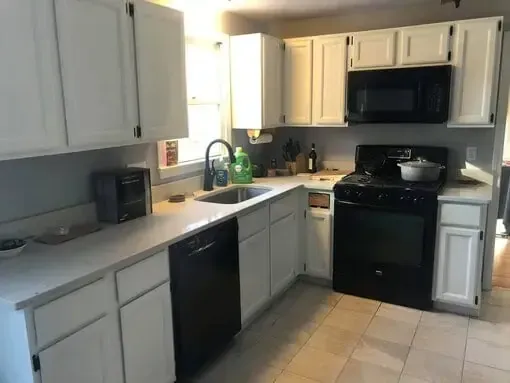 Small kitchen with white cabinets, black appliances, a sink, and beige tile floor