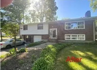 Suburban split-level house with brick and white siding, front walkway, and sunny green lawn