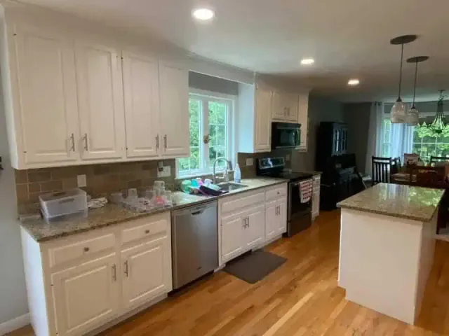 Bright modern kitchen with white cabinets, granite counters, stainless appliances, and hardwood floors