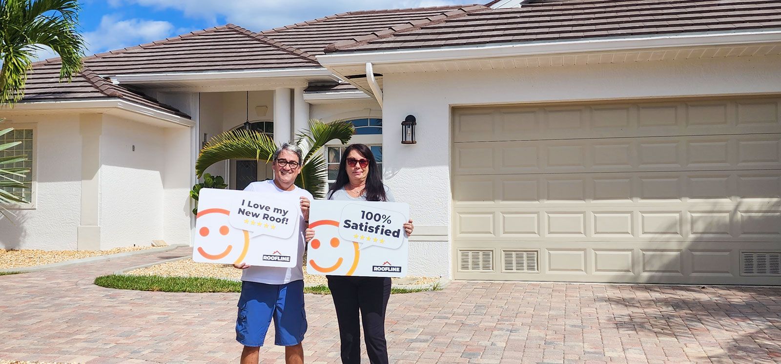 A man and a woman are holding signs in front of a house.