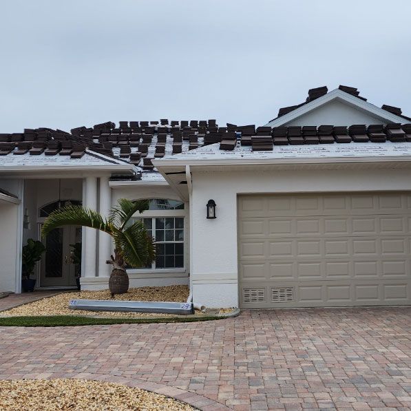 A white house with a brown garage door and a brick driveway