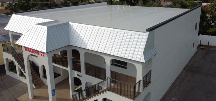 An aerial view of a large white building with a white roof.