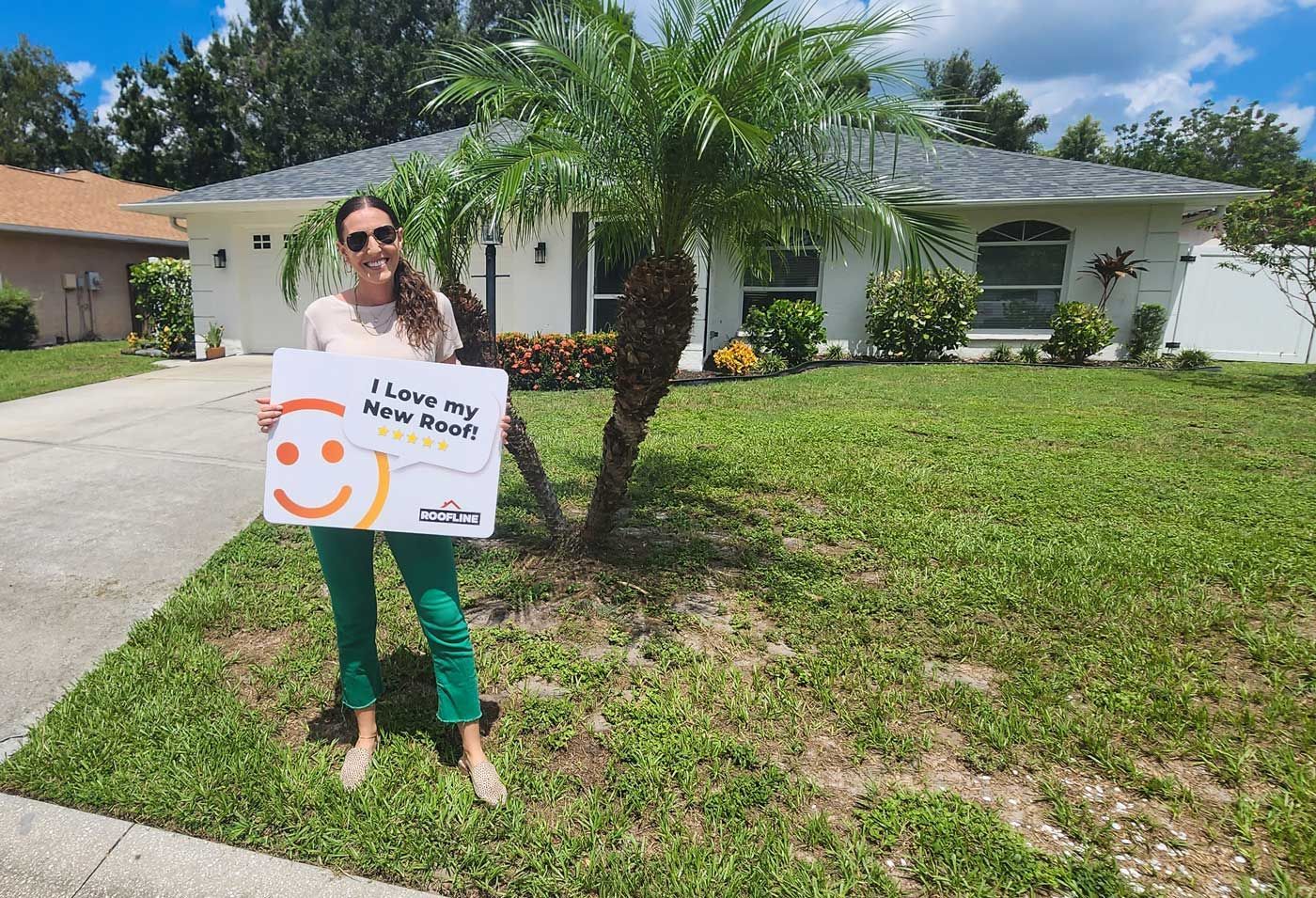 A woman is holding a sign in front of a house.