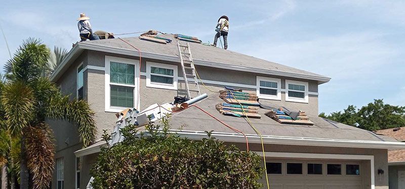 Two men are working on the roof of a house.