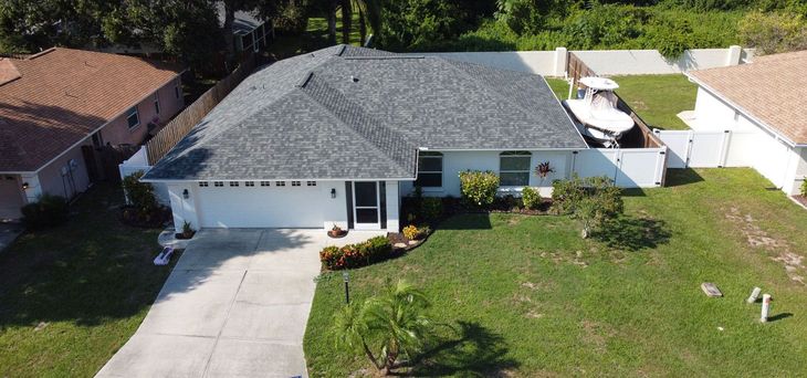 An aerial view of a house with a boat in the driveway.