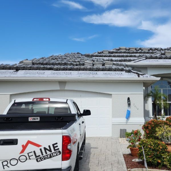 A roofline truck is parked in front of a house