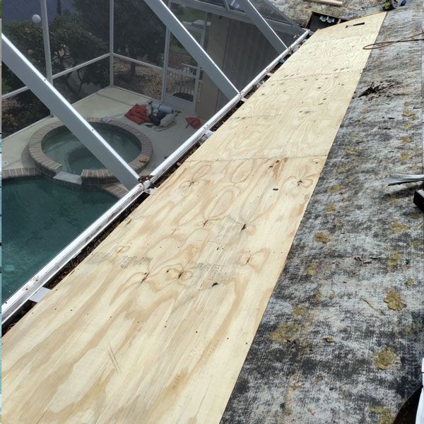 A large piece of plywood is sitting on top of a roof next to a pool