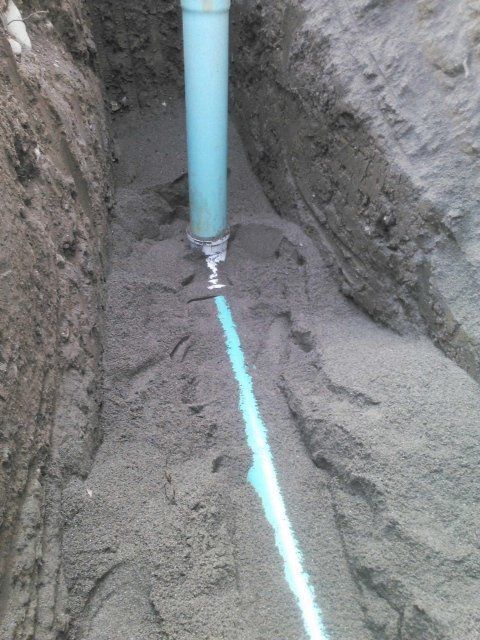 a blue pipe is laying in the dirt in a trench .