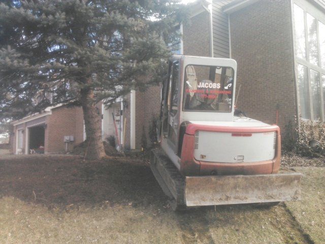 a red and white excavator is parked in front of a house .