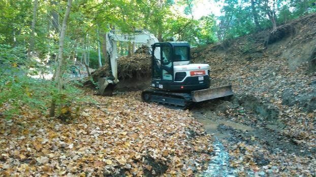 a bulldozer is digging a hole in the woods .