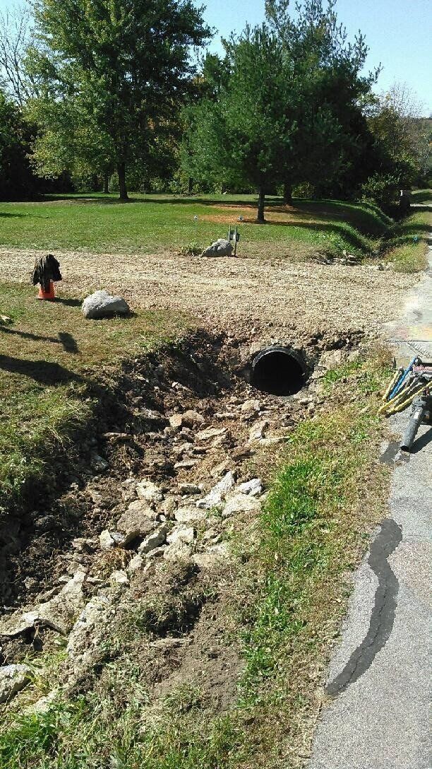 a person is digging a hole in the ground next to a road .