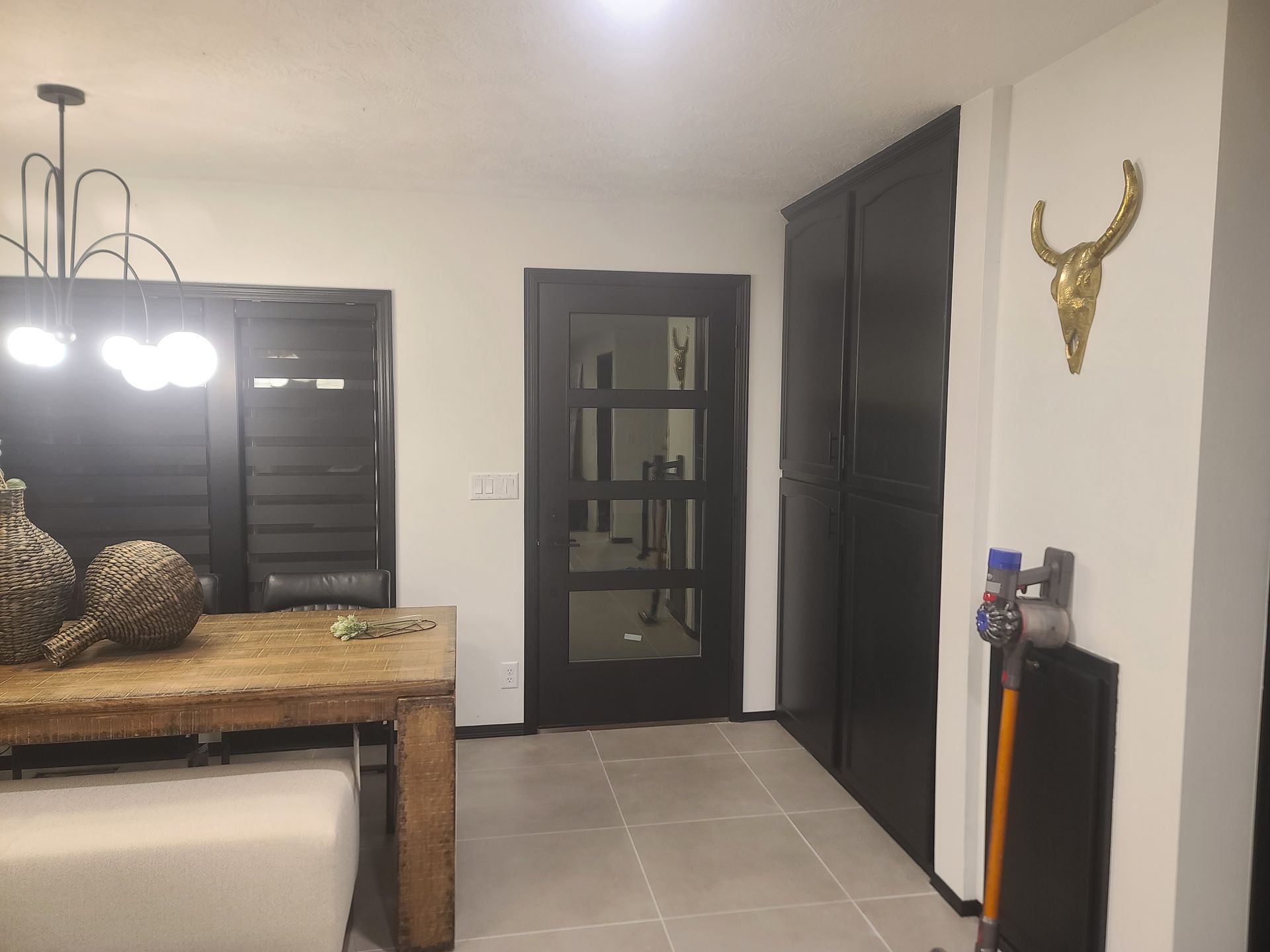 Dining room with wooden table, dark door and cabinets, gold skull decor.