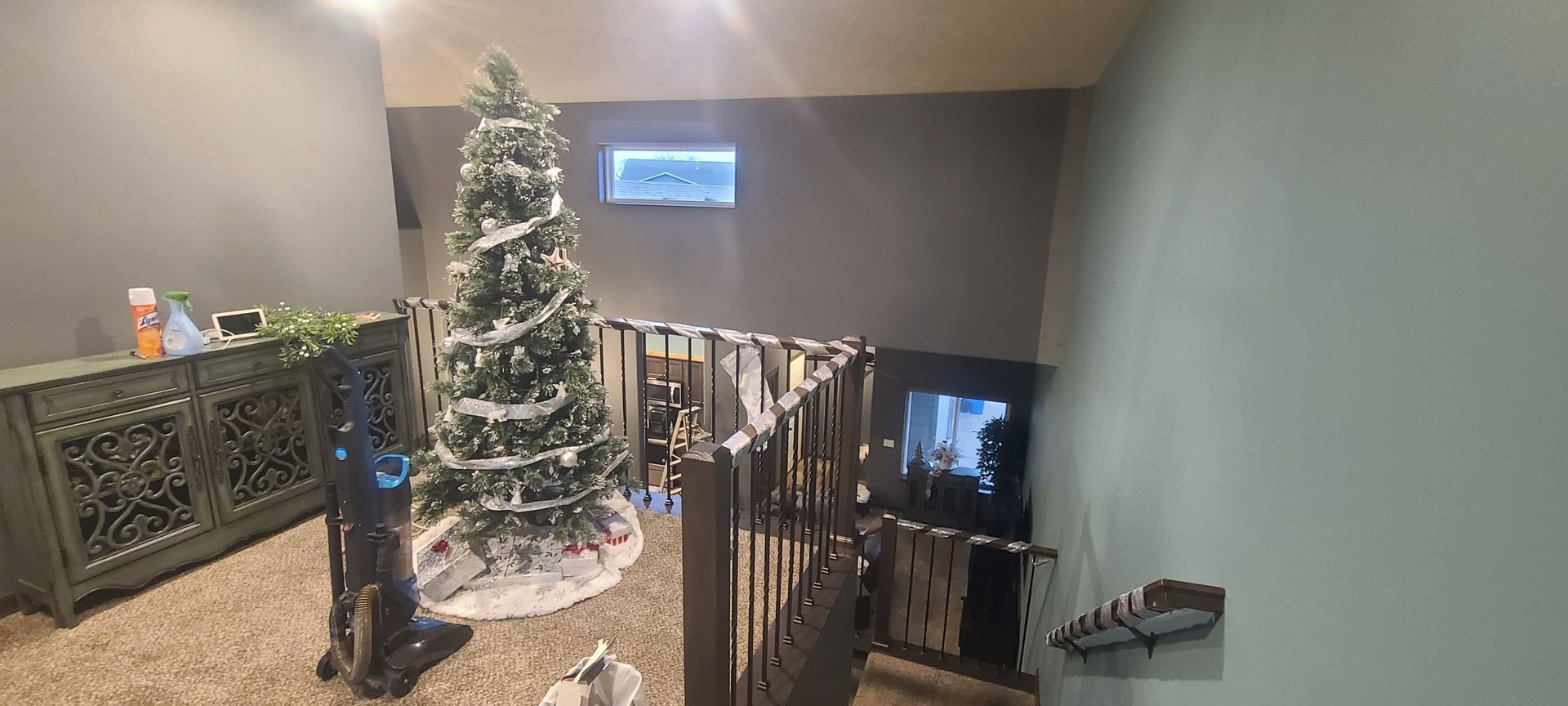 Interior room with Christmas tree, decorative furniture, and staircase.