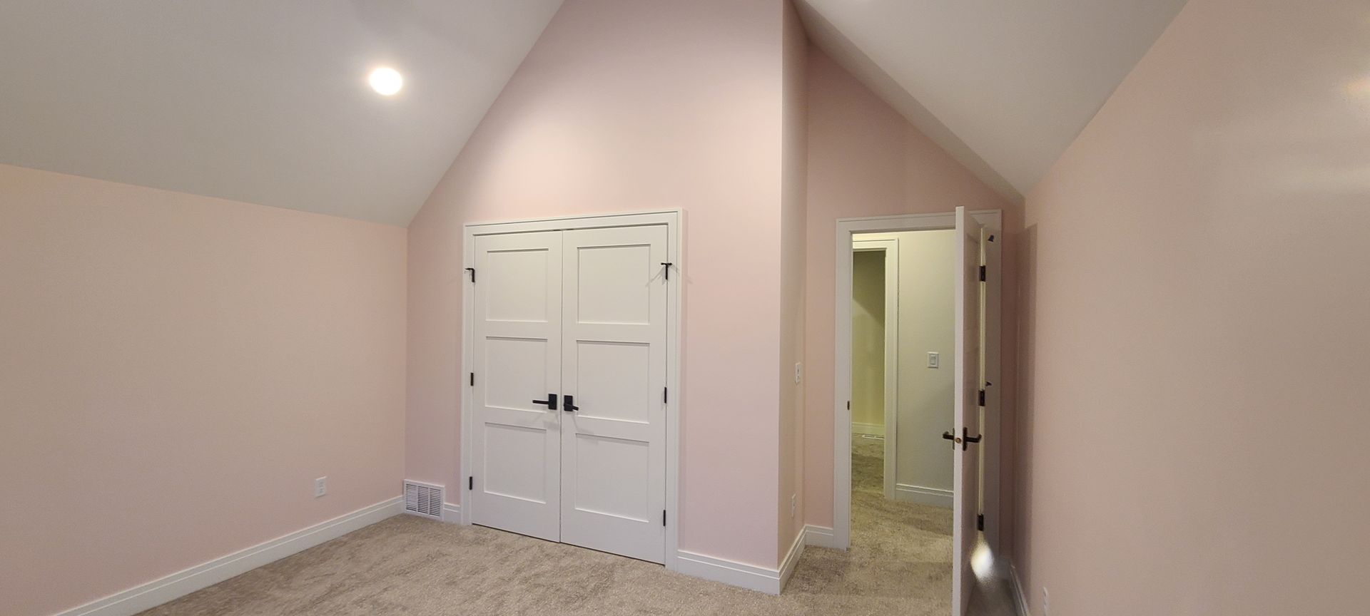 A pink bedroom with white double doors, a door to another room, and a carpeted floor.