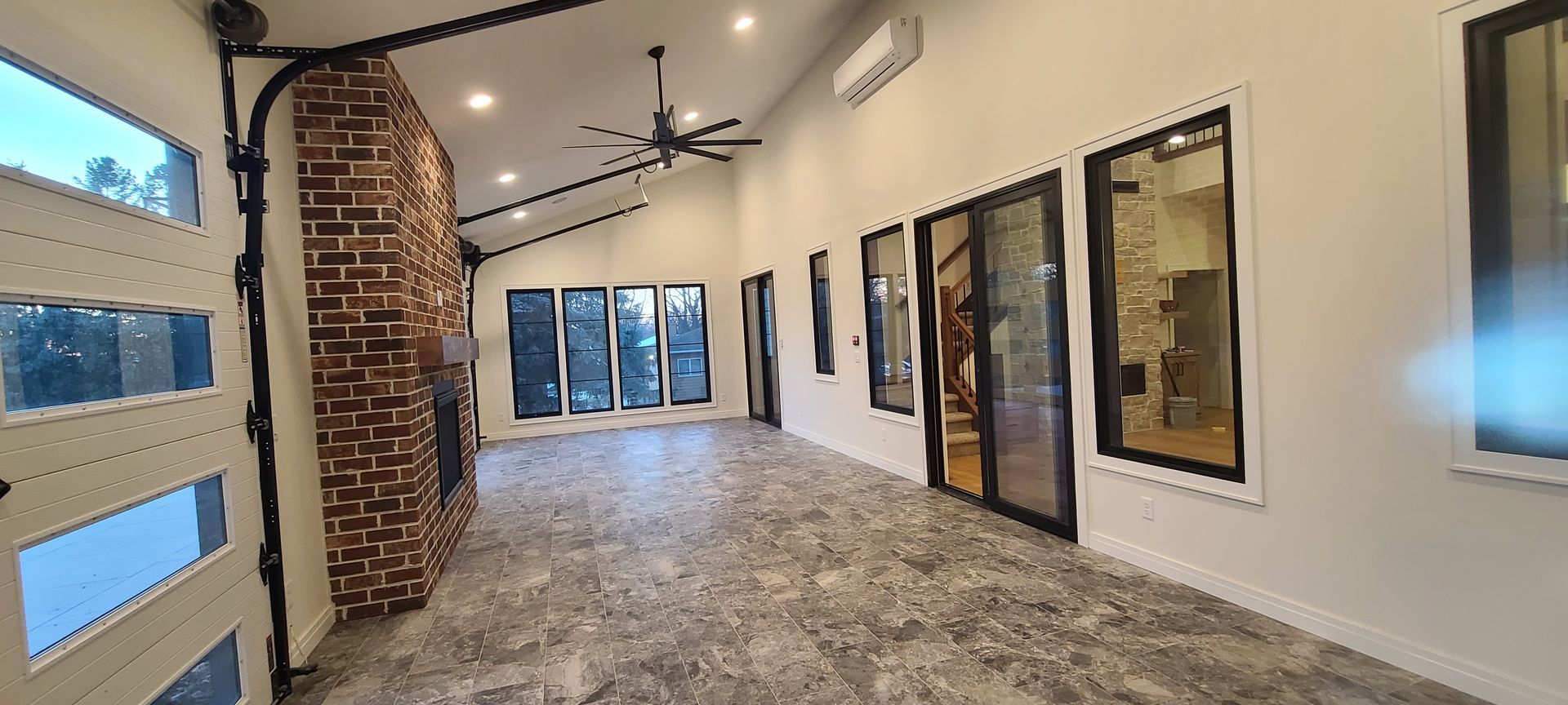 Spacious interior with exposed brick fireplace, large windows, and a garage-style door.