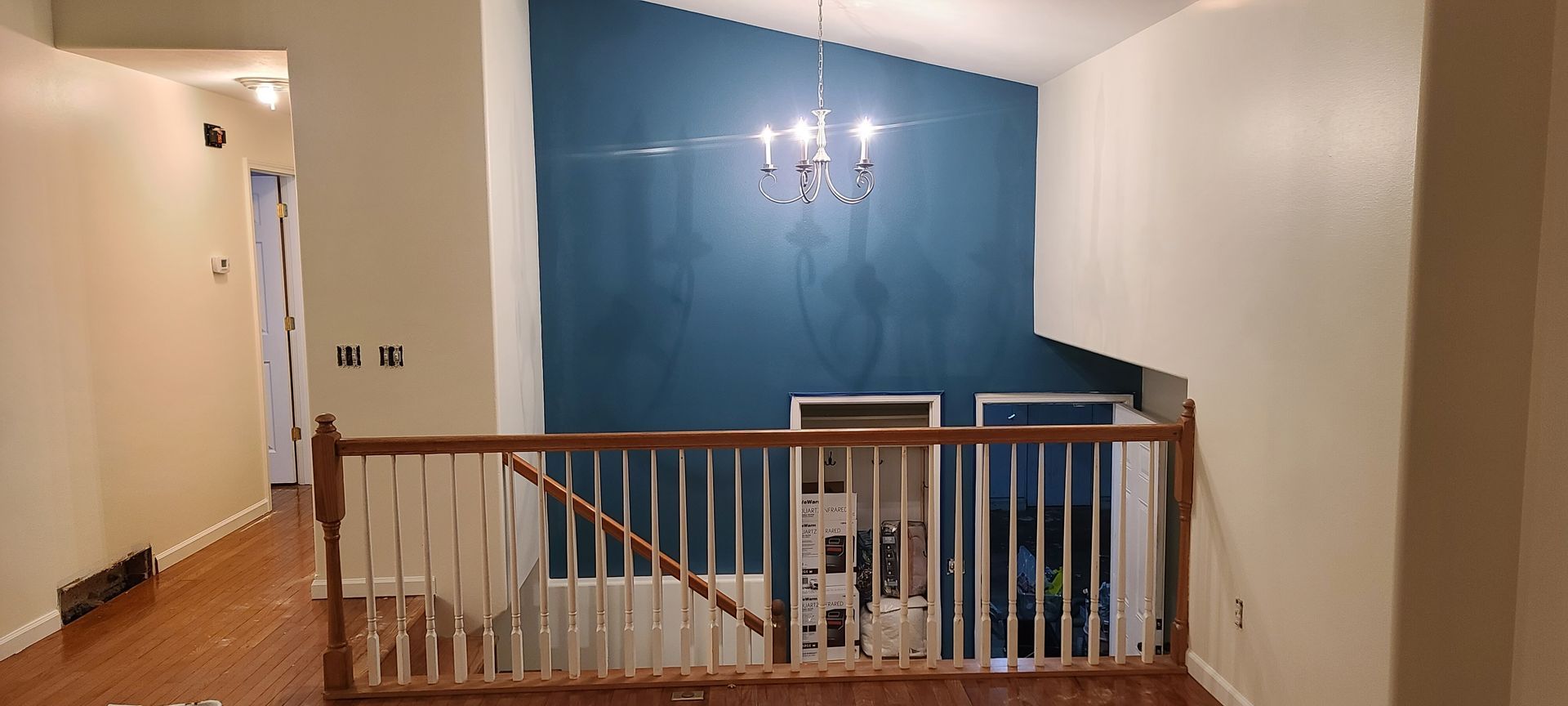 Interior view of a two-story home with blue accent wall and wooden banister.
