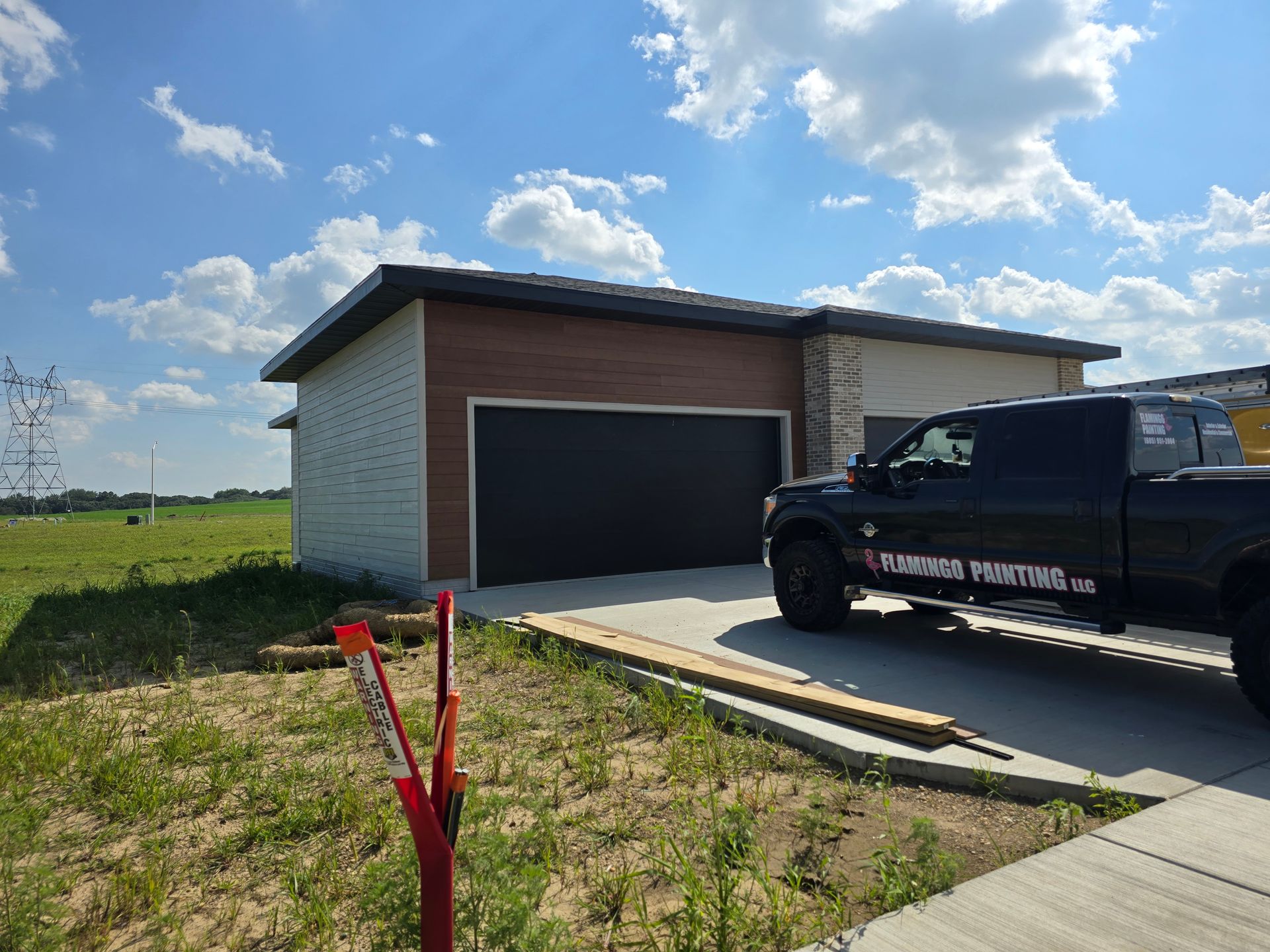 Black truck parked in front of a modern house with a black garage door.