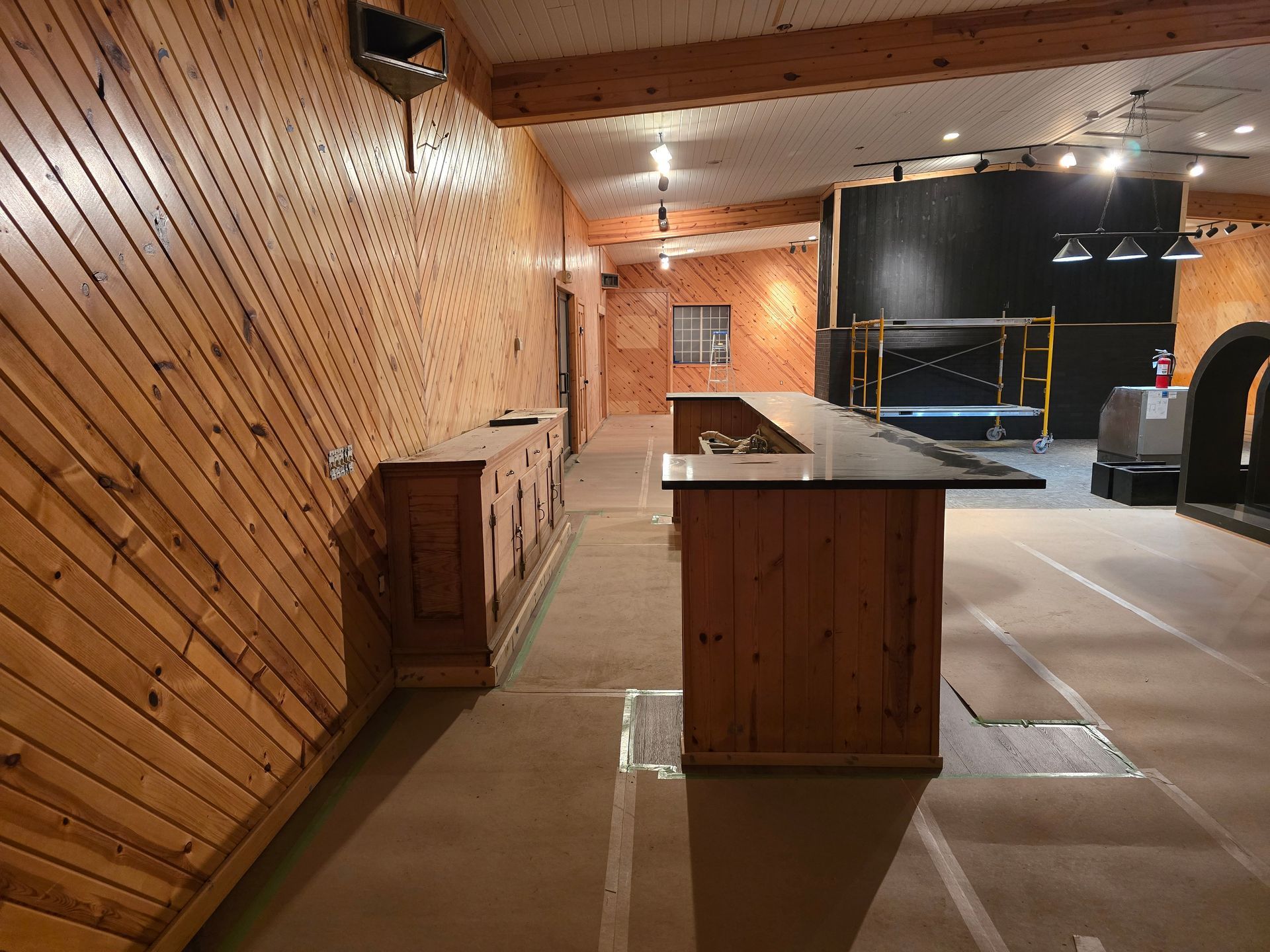 Wood-paneled bar interior with counter, doors, and a performance area in the background.