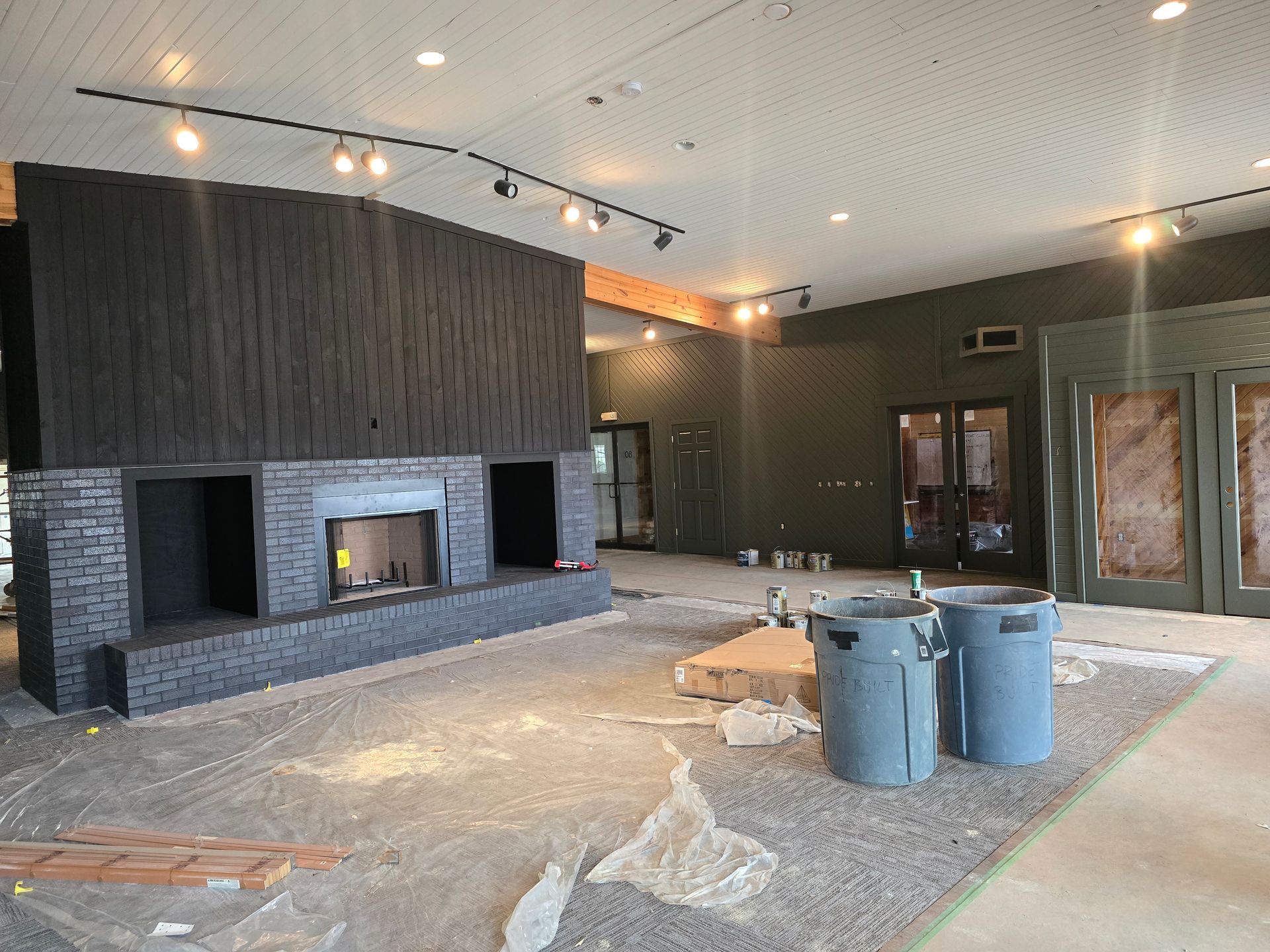 Newly constructed room with a large brick fireplace and modern lighting.
