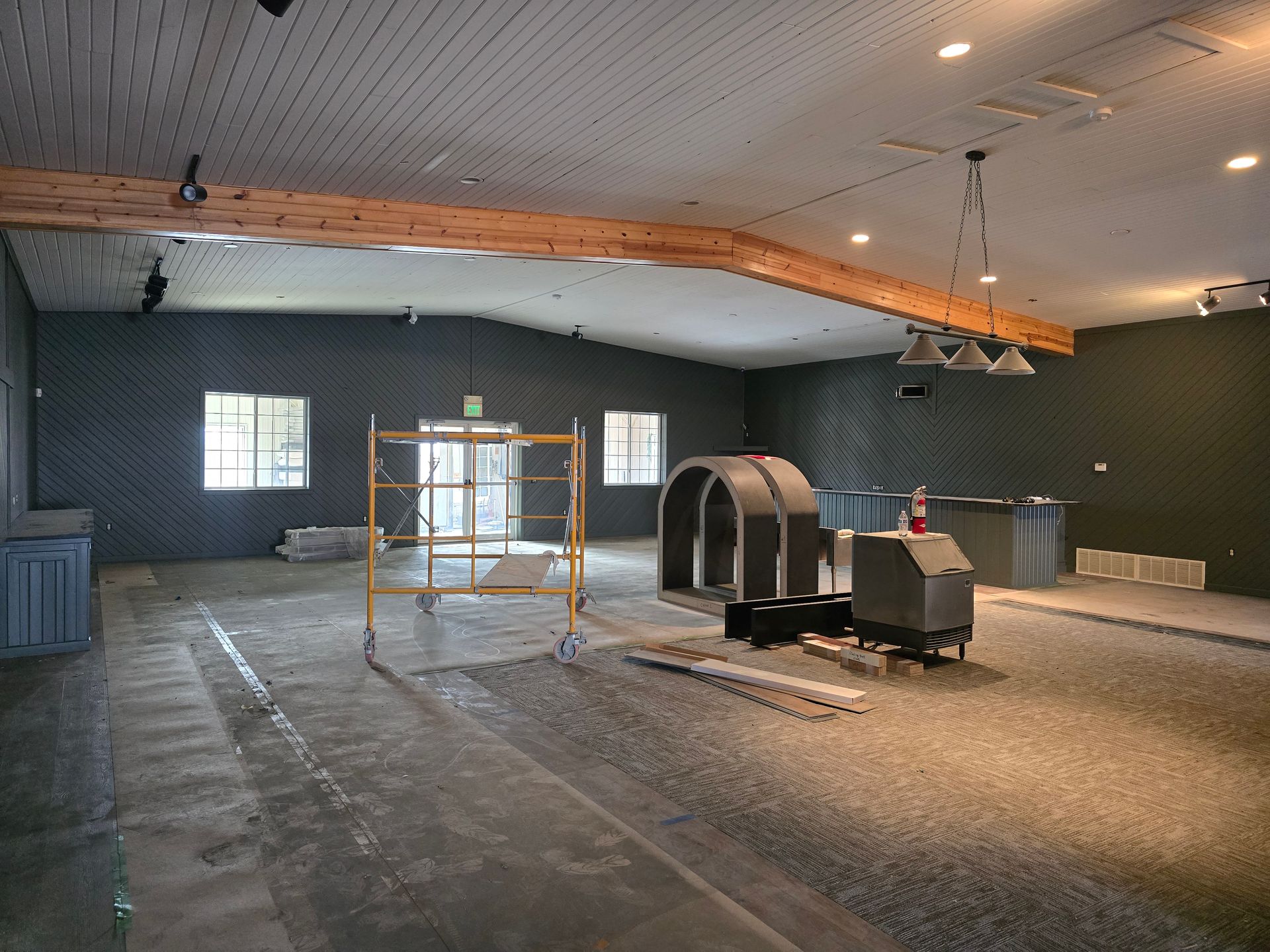 Interior of an unfinished room with scaffolding, construction materials, and dark green walls.