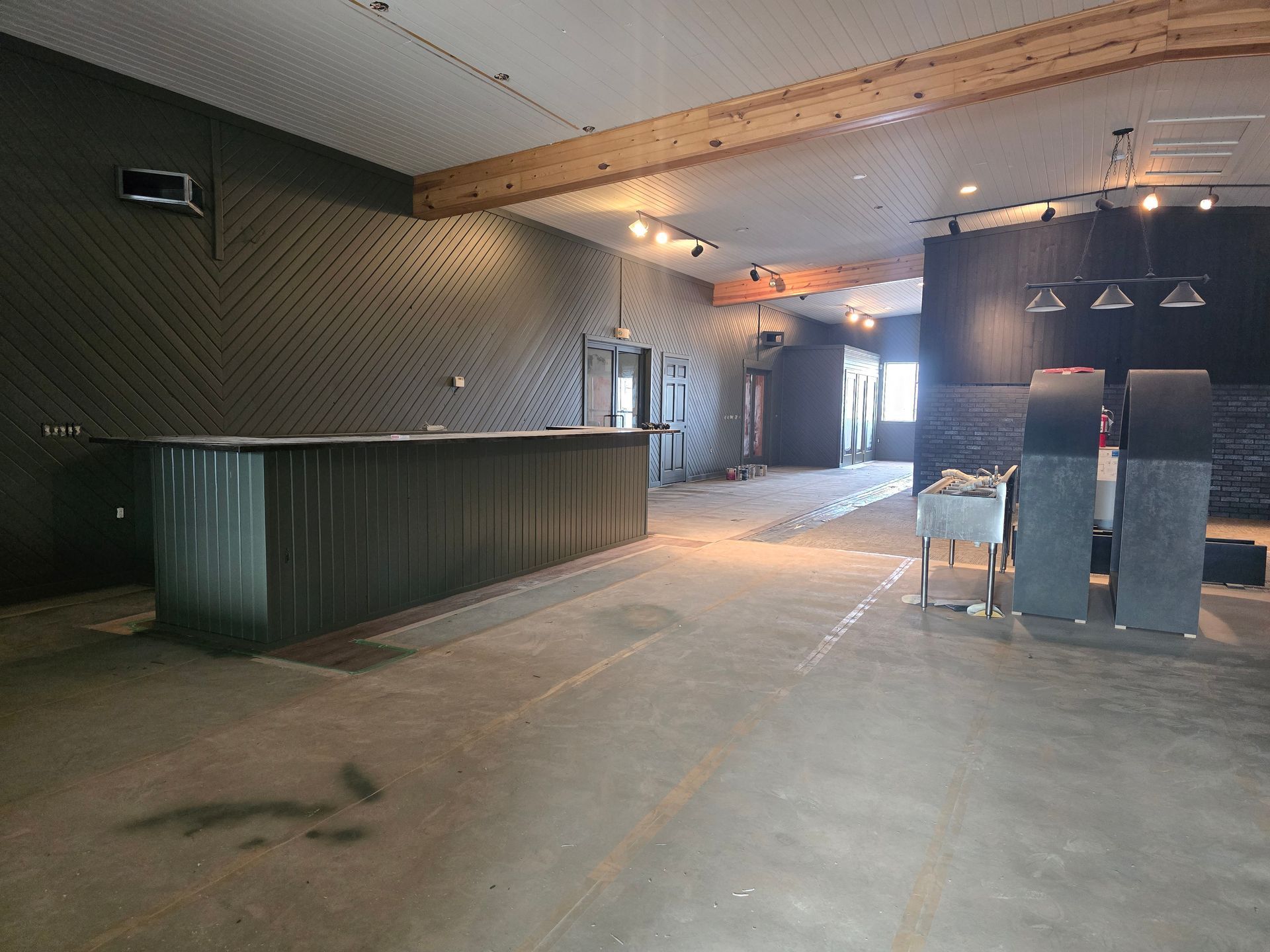 Empty commercial space with a corrugated metal bar and dark gray walls.