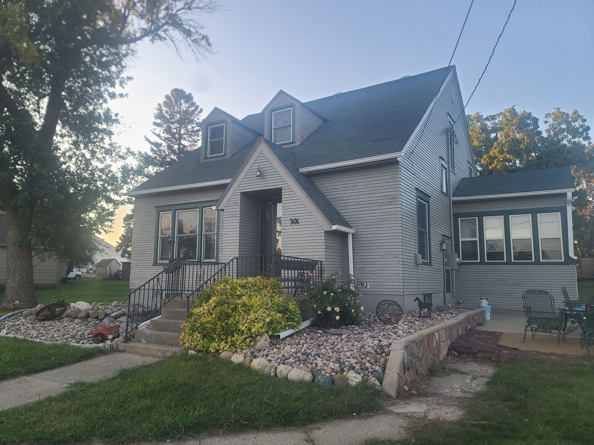 Gray house with dormers, steps, and landscaping.