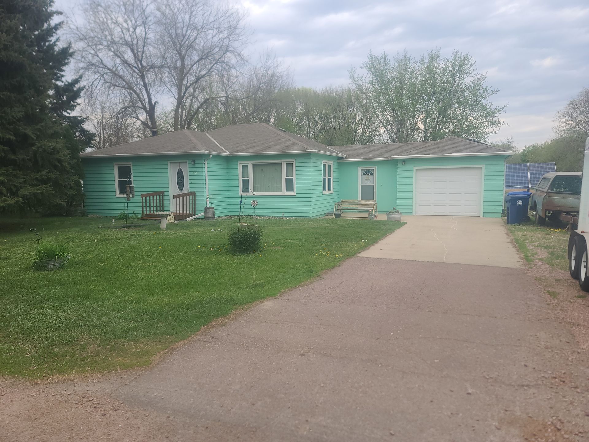 A one-story house with light green siding and a concrete driveway.