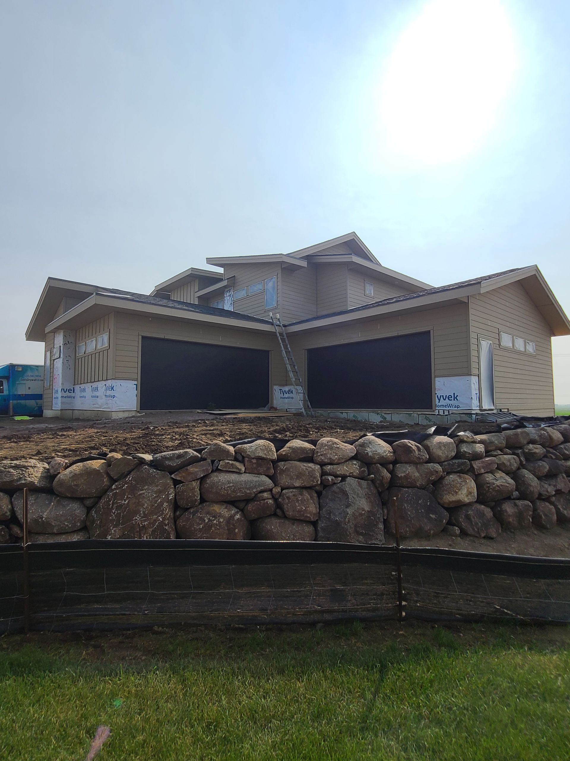 House under construction with stone retaining wall.