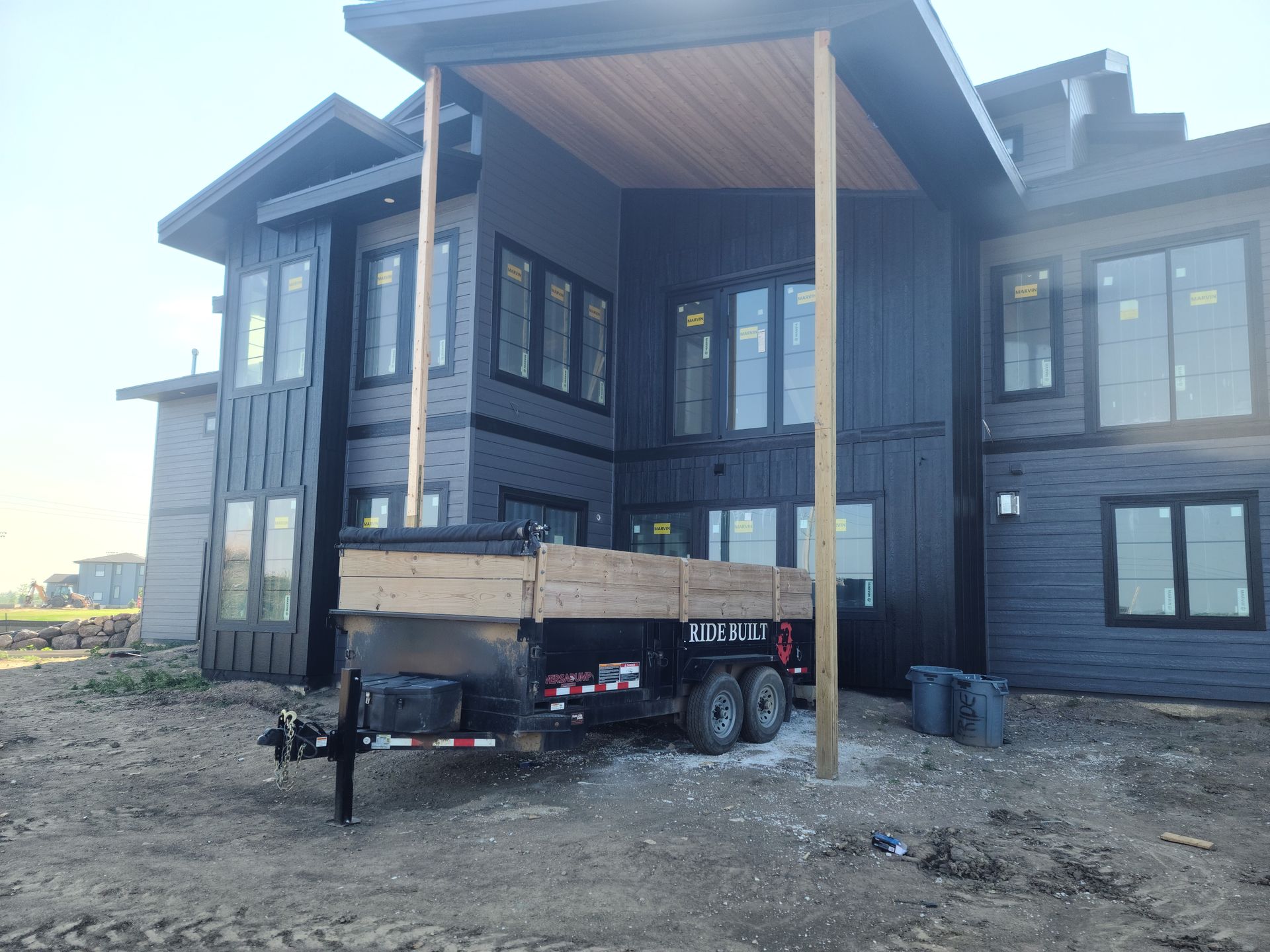 Black modern house under construction with a trailer parked in front.