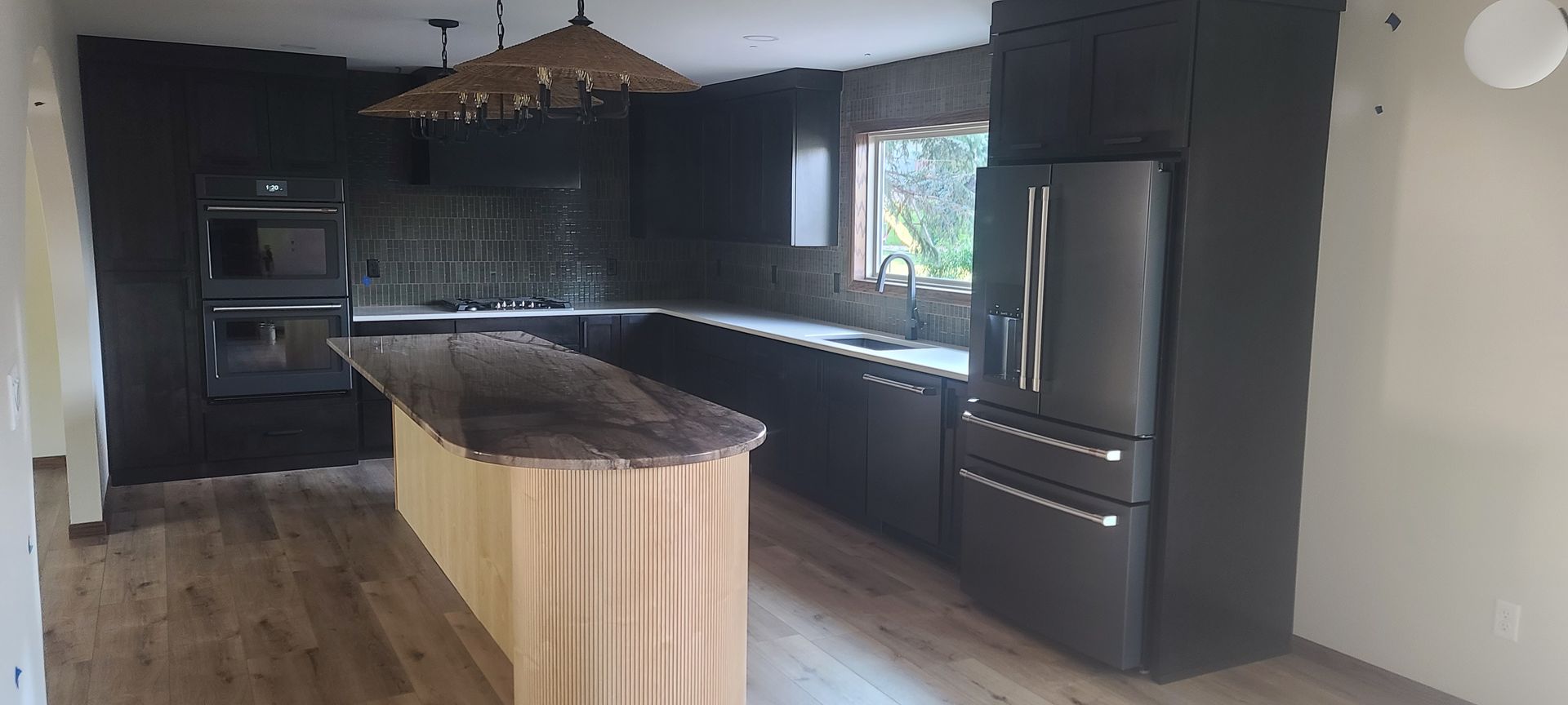 Modern kitchen with dark cabinets, a light wood island, and a stainless steel refrigerator.