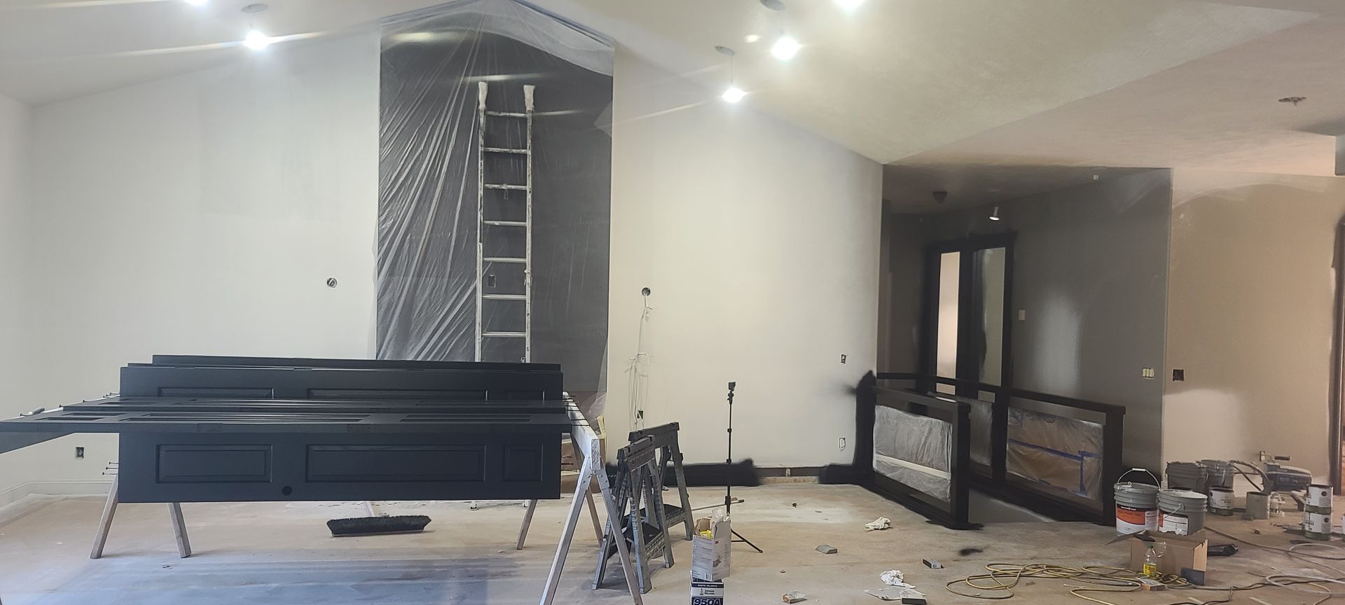 Interior renovation of a room with a ladder, tools, and construction materials.