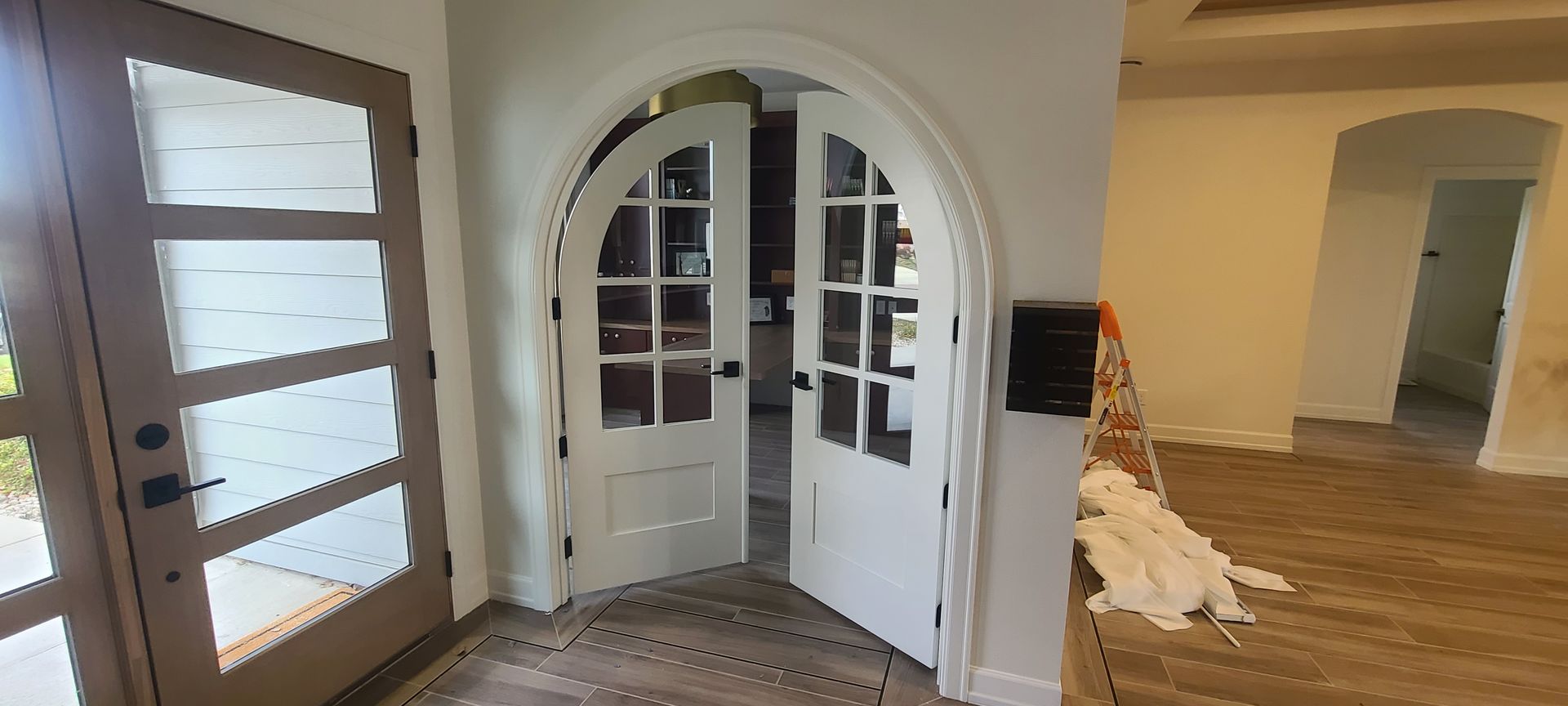 Interior view of an entryway with arched doors and a wooden front door.