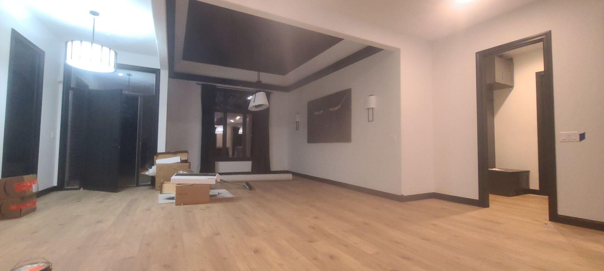 Empty room with wood floors and recessed lighting. Partially furnished with boxes on the floor.