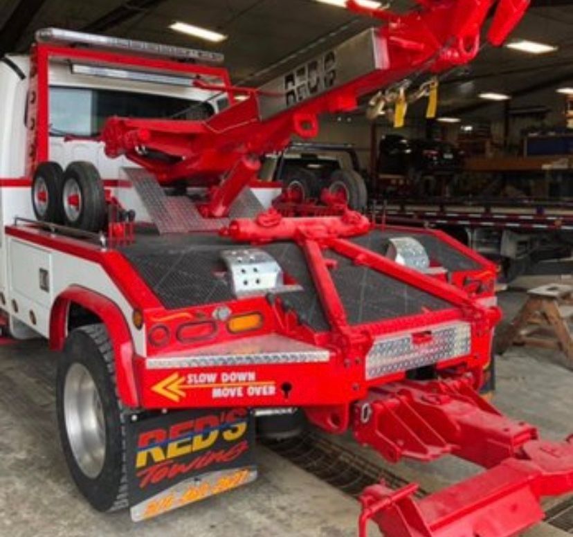 A red and white tow truck is parked in a garage