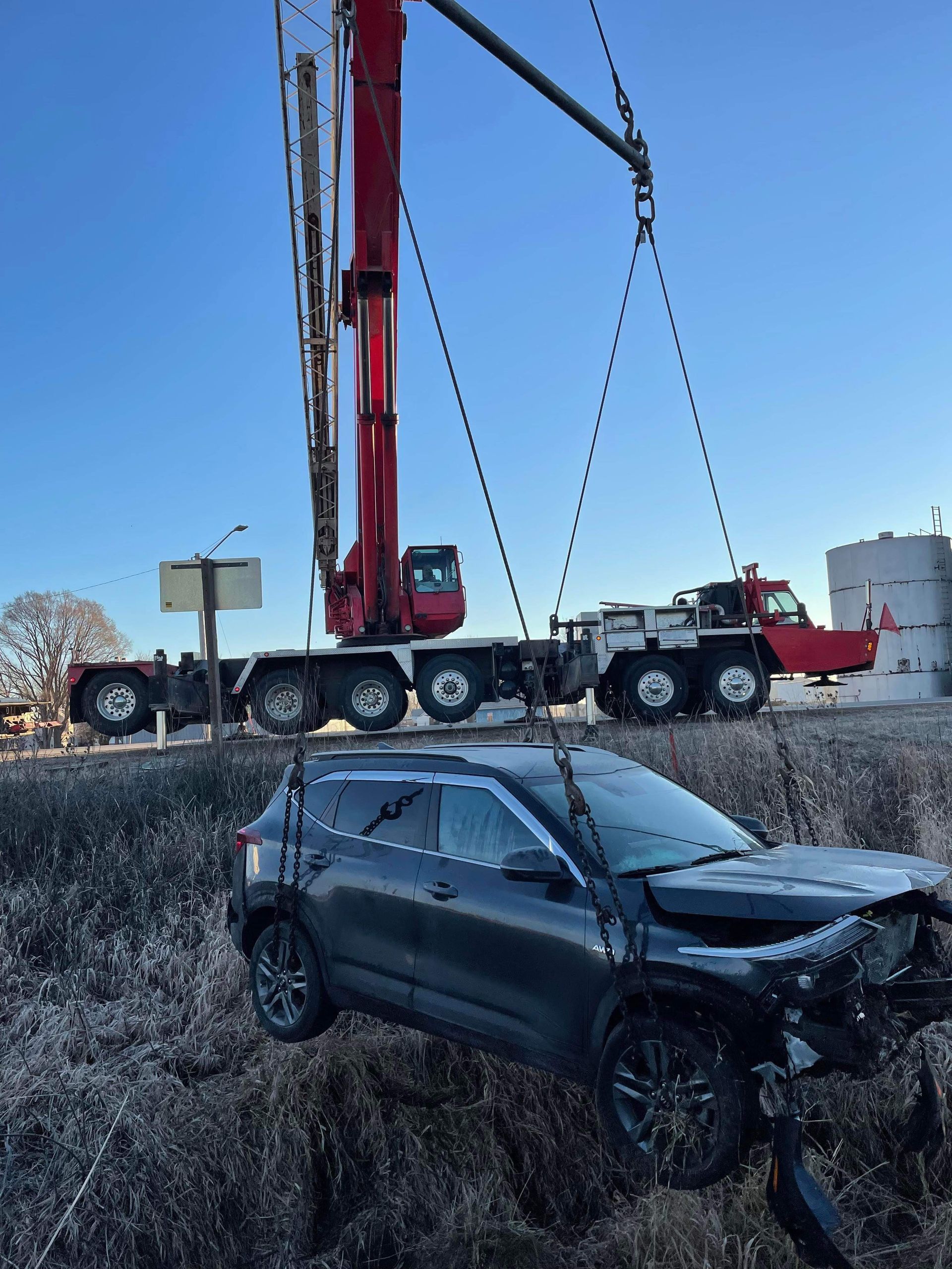 A car is being lifted by a crane in a field