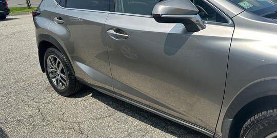 Side view of a silver SUV parked on gravel. The car door handle is visible.