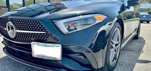 Black Mercedes-Benz is parked outdoors on a sunny day.
