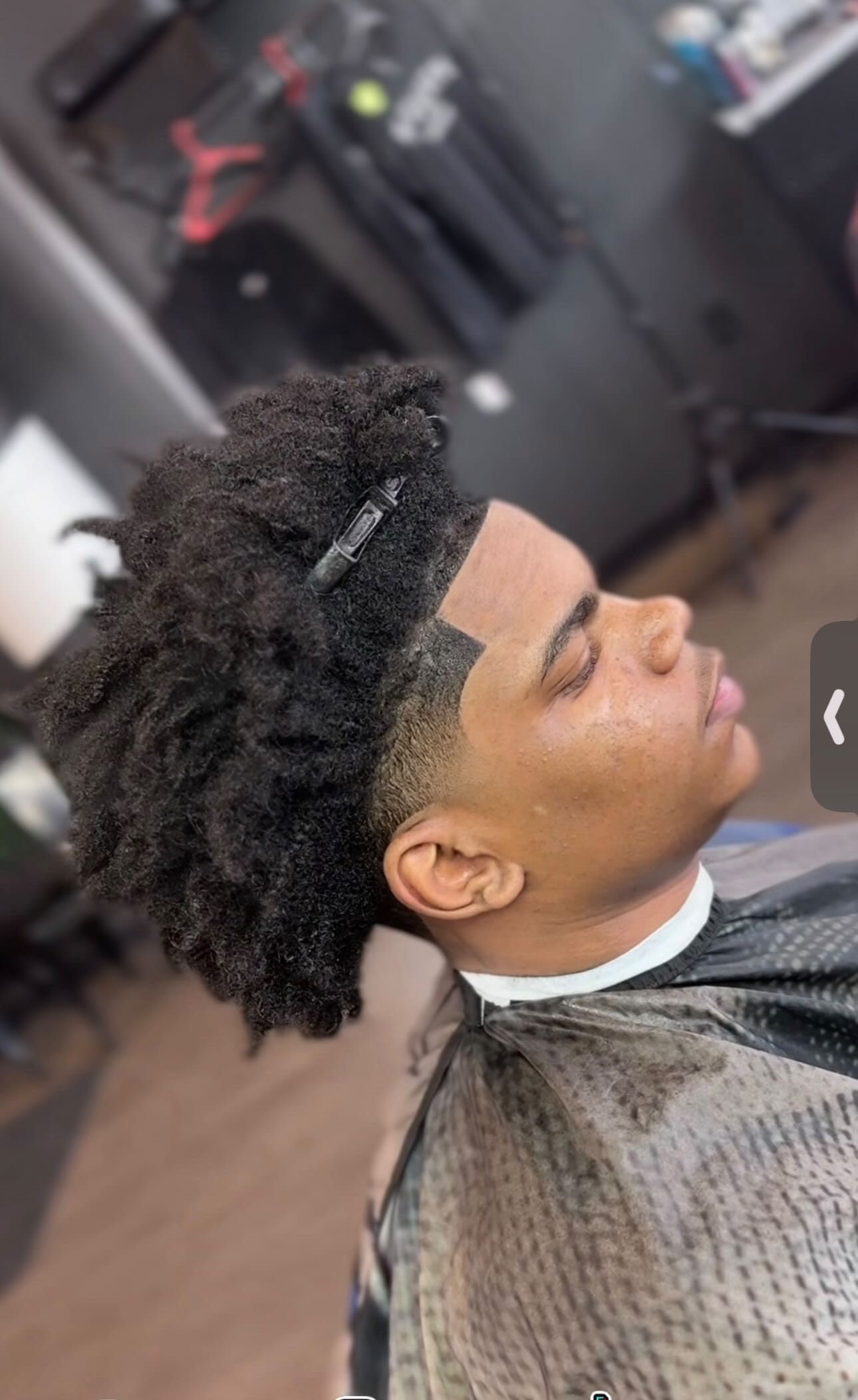 Man with short dark hair, fresh haircut, side profile, barbershop setting.