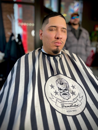 Man in barber cape with fresh haircut at a barbershop.