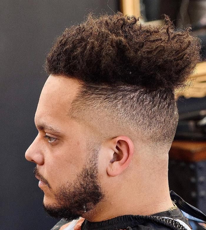 A man with a beard is getting his hair cut at a barber shop.
